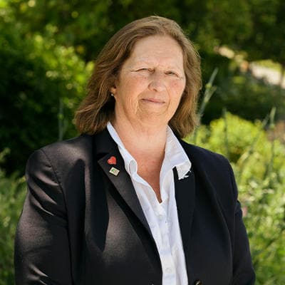 A female funeral arranger with shoulder length hair smiles gently to camera